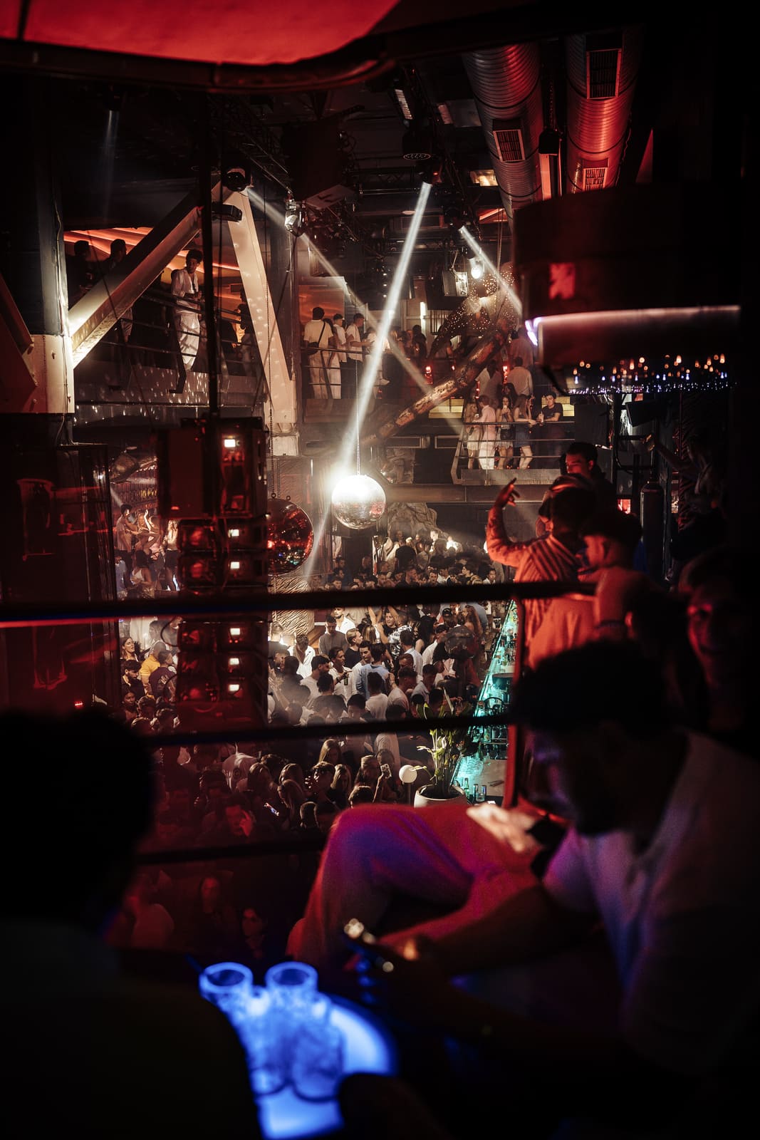 Overhead view of a packed club with disco balls and dramatic lighting.