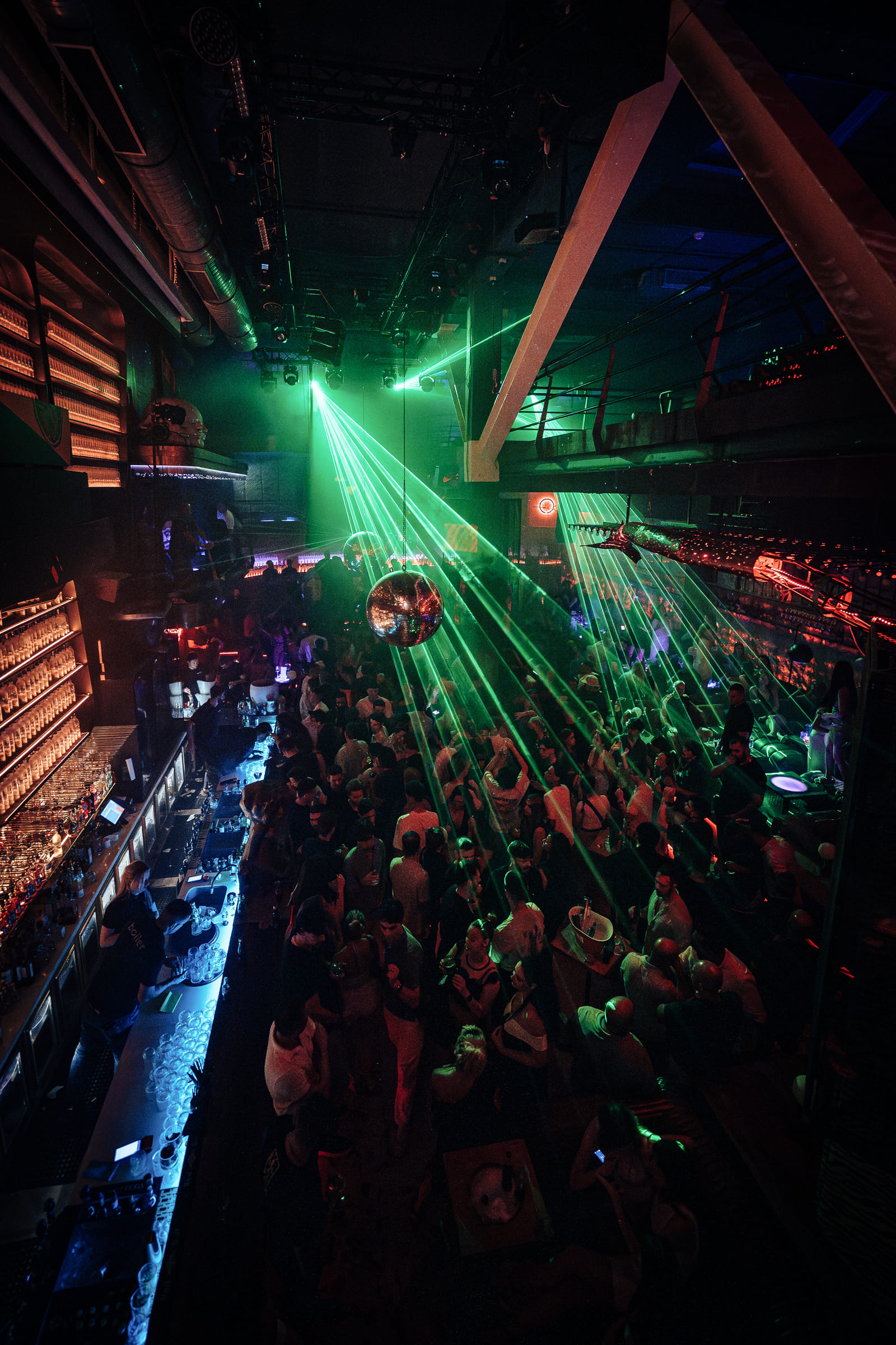 Aerial view of crowded bar and dance floor with green lasers.