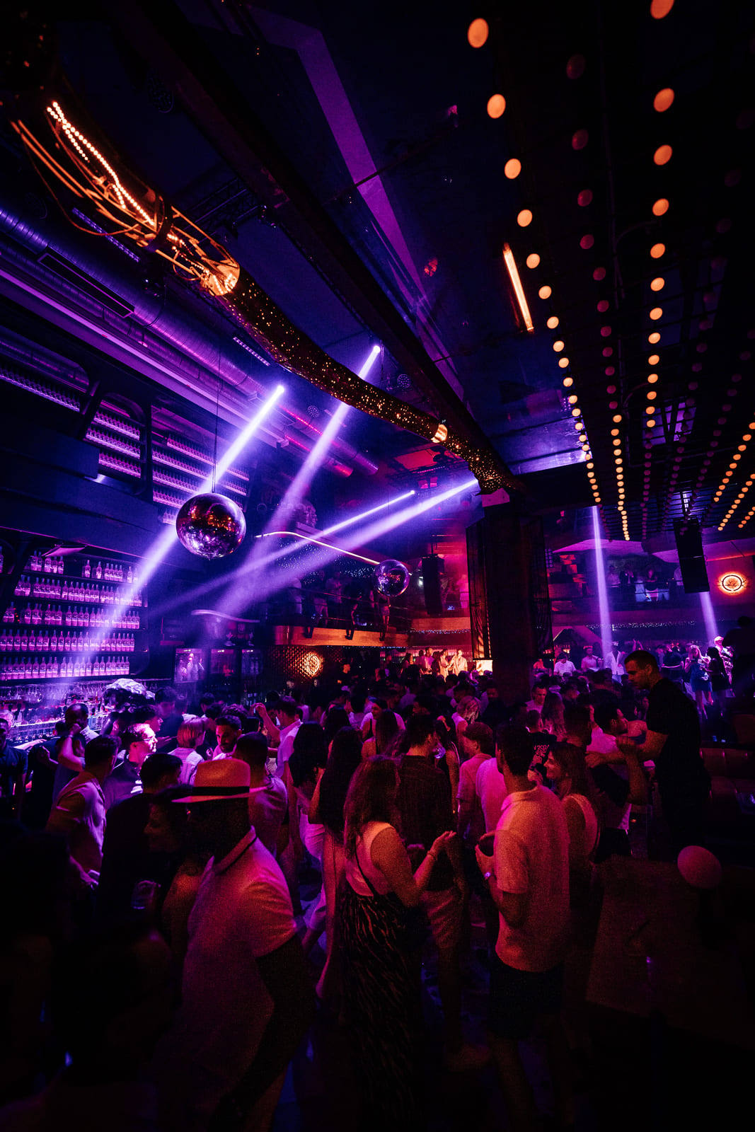 Crowd dancing under purple lights in a packed nightclub