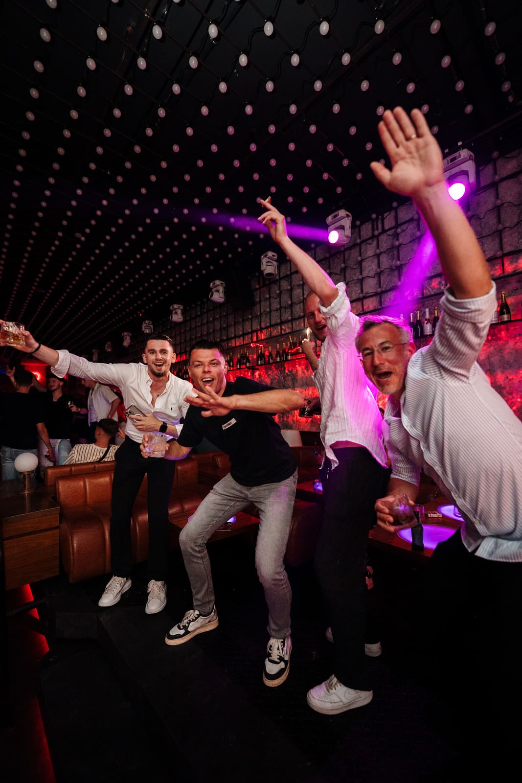 Group of men celebrating with drinks in a nightclub lounge Title: group_celebrating_nightclub_lounge