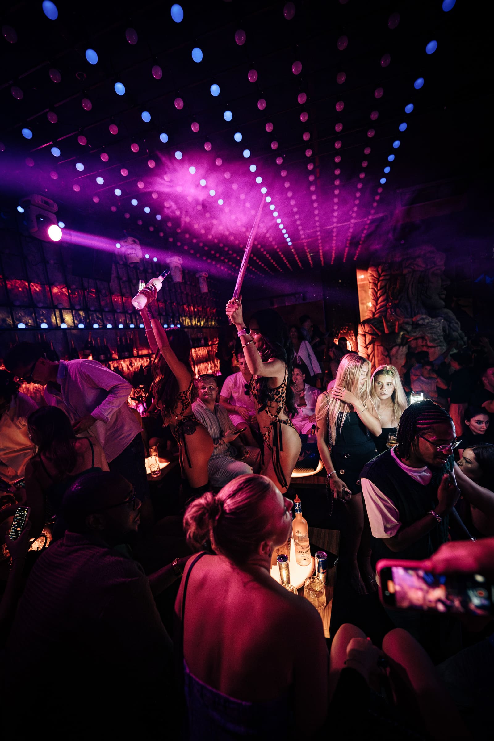 Bottle service presentation with pink fog and vibrant lights.