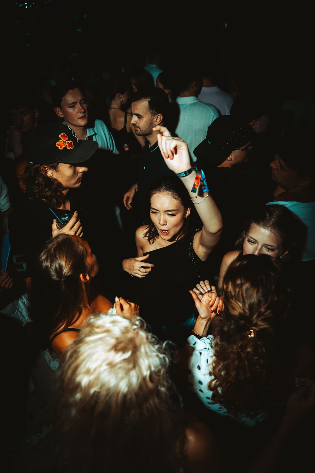 Woman with arm raised dancing in the middle of a packed club crowd