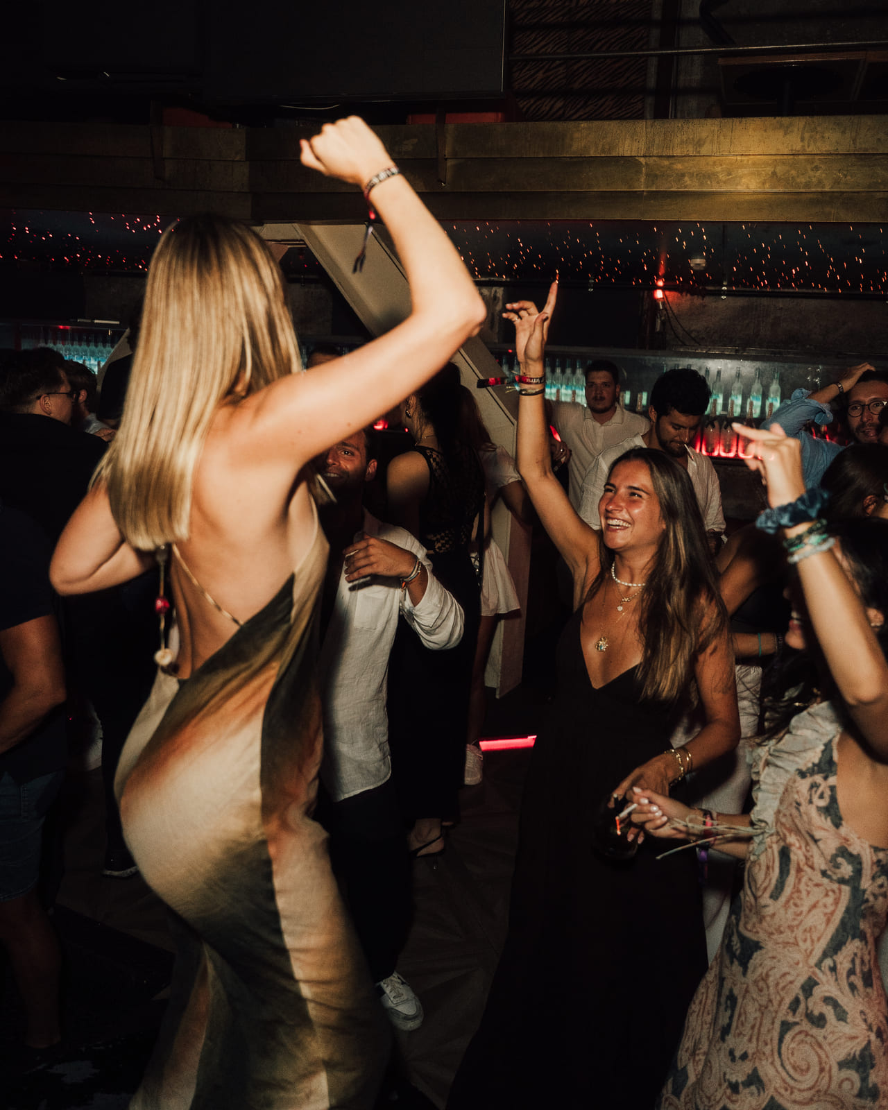 Women celebrating and dancing with hands in the air at a lively nightclub