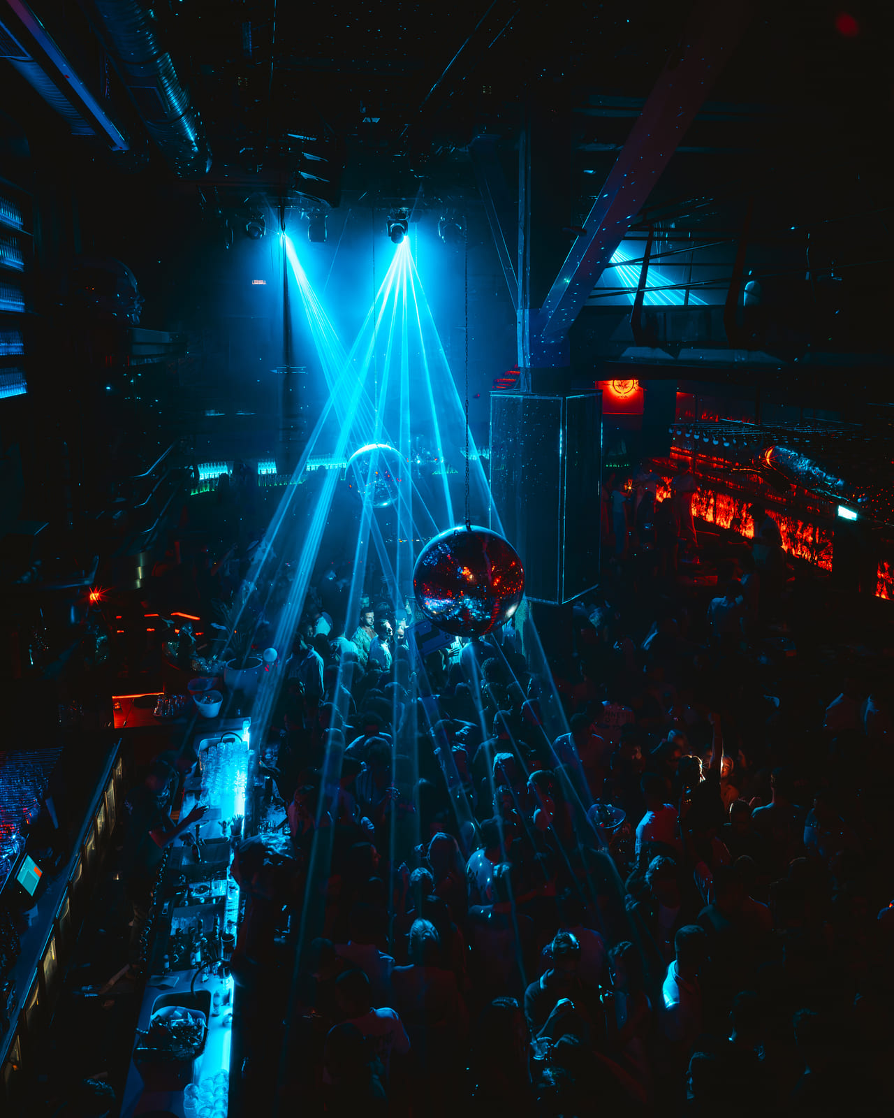 verhead view of a packed nightclub with blue laser lights and disco ball