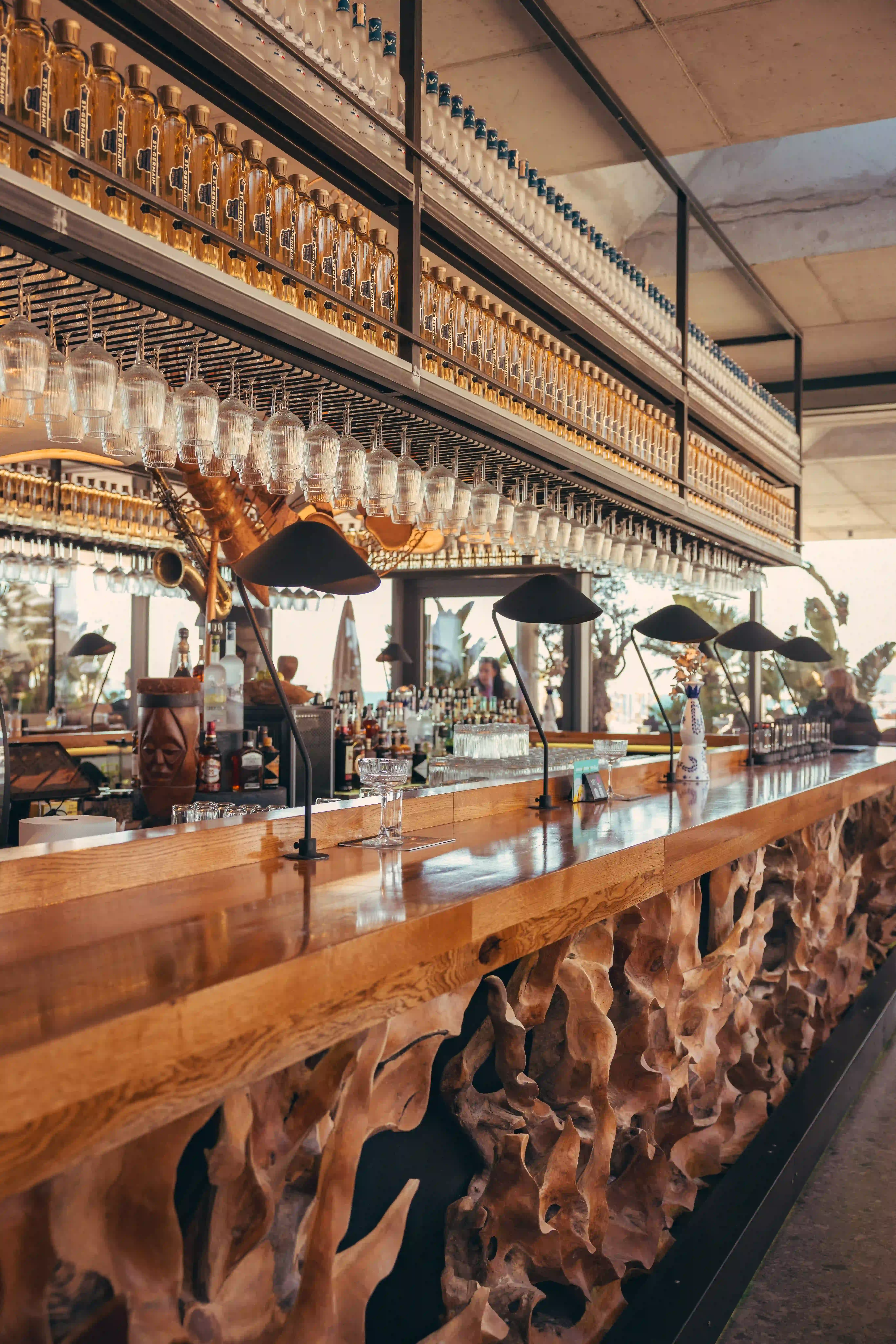 Interior view of Miyu Beach bar with wooden counter and hanging glassware.