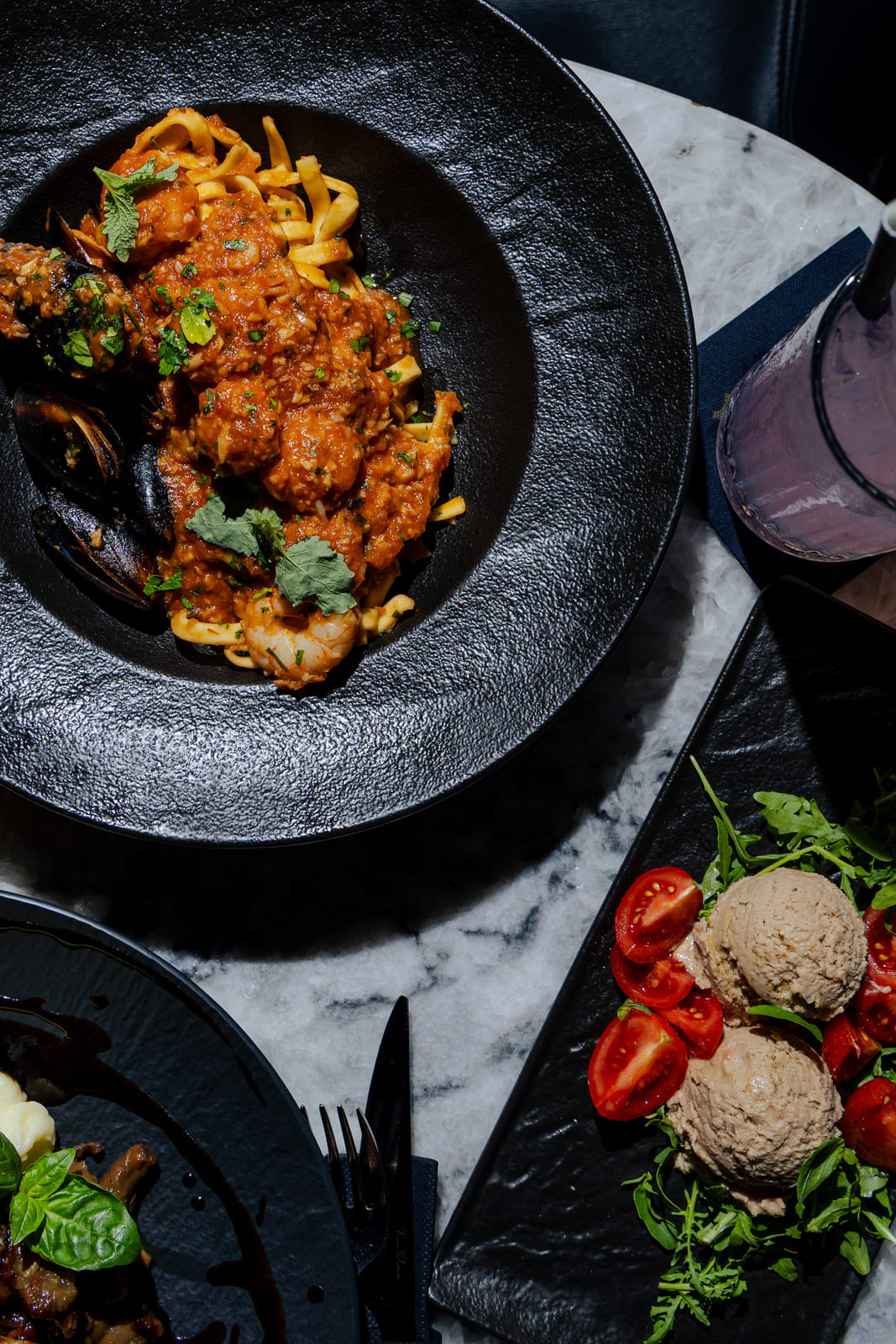 Seafood pasta with shrimp and mussels in a tomato sauce, served on a marble table.