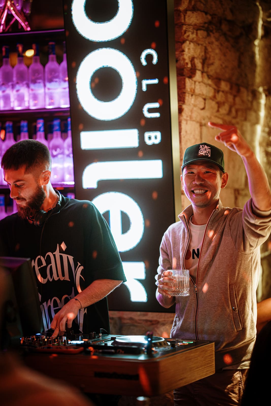 DJ performing while guests dance and celebrate beside the Boiler Club sign.