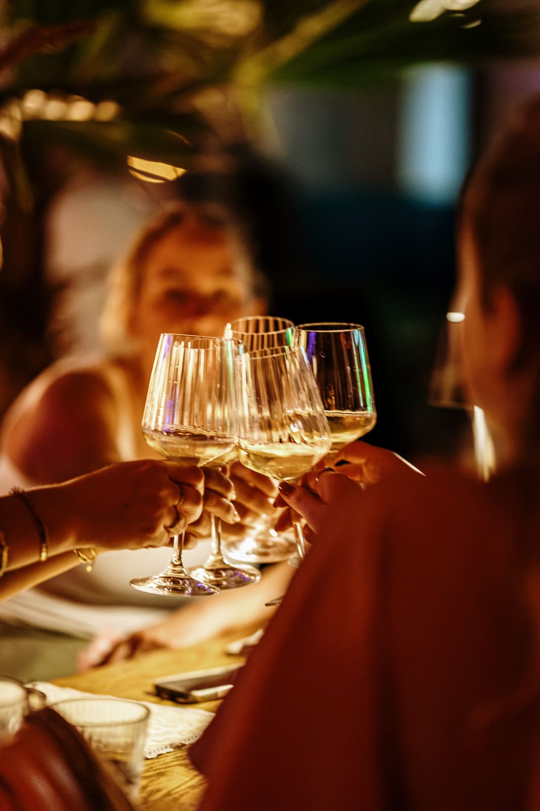 Group of friends clinking wine glasses at a dinner table