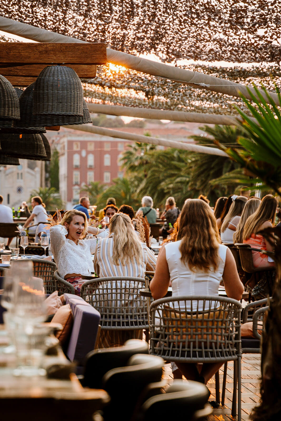 Group of women dining together at an outdoor restaurant patio during golden hour.
