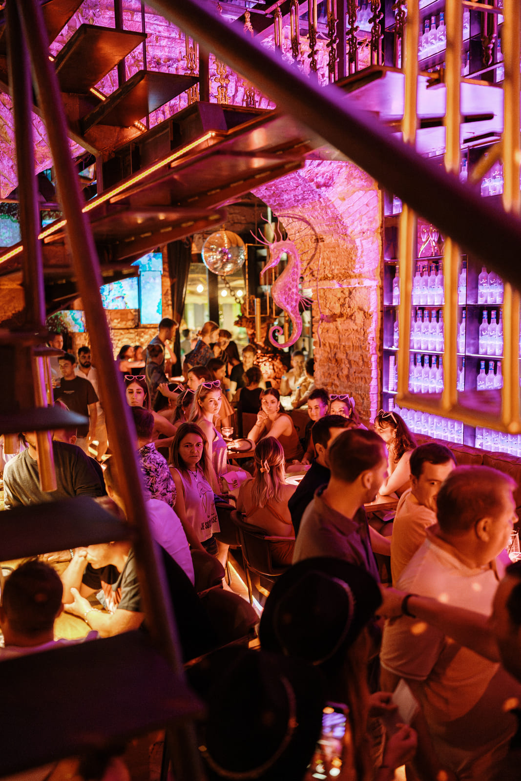 Packed restaurant with warm lighting, a seahorse wall art, and a disco ball.